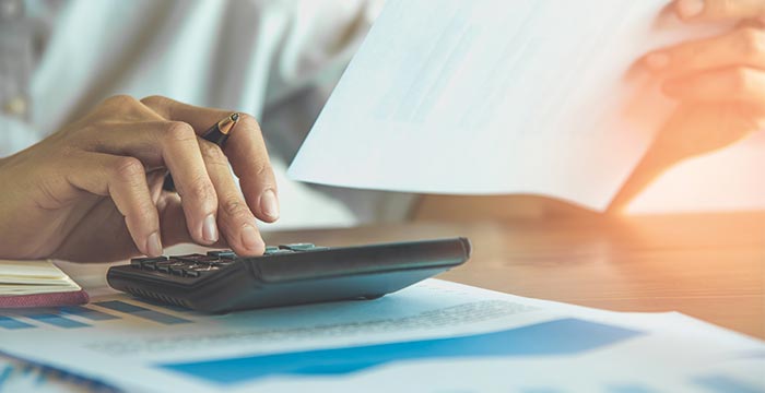 Mãos digitando em uma calculadora
